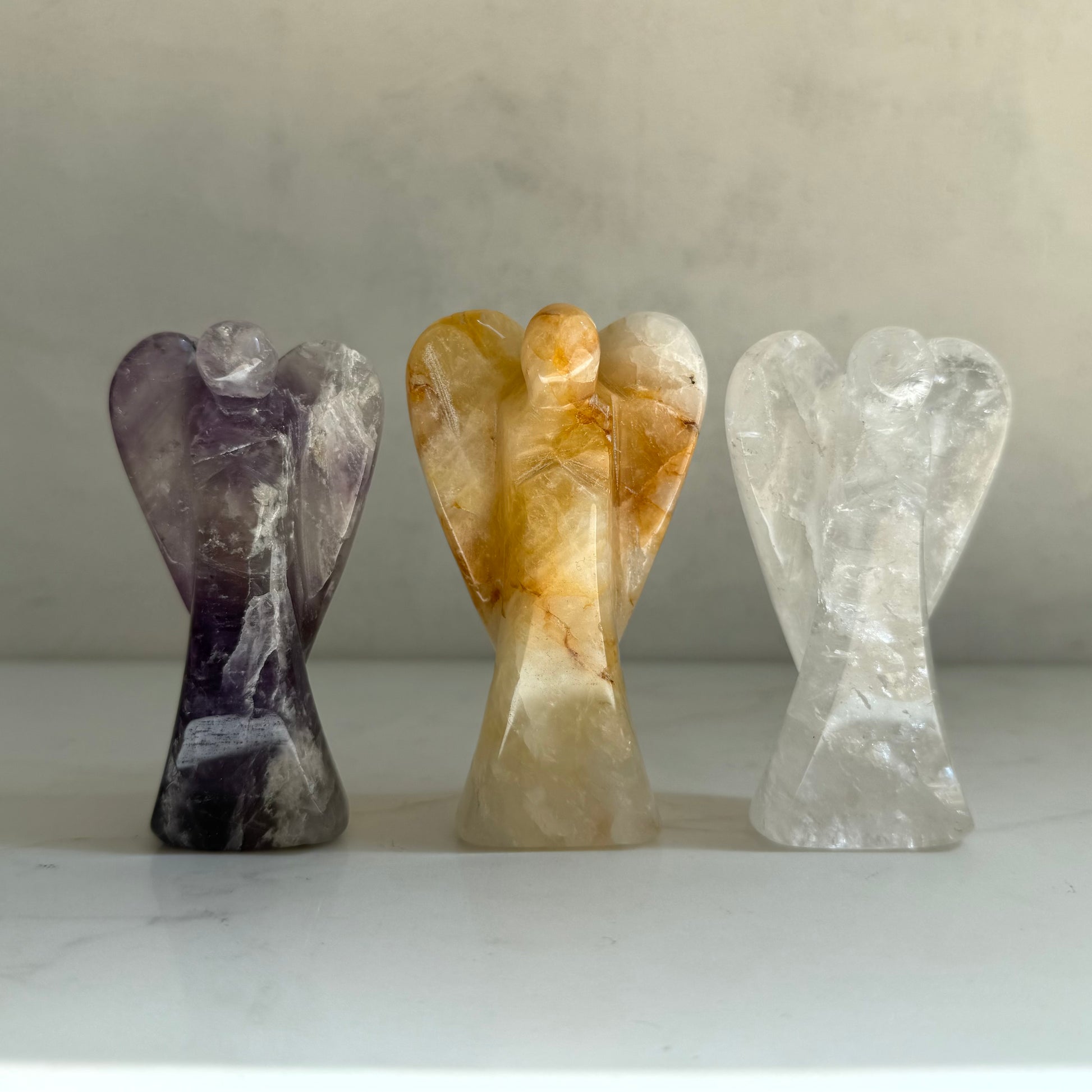 Guardian Angel Trinity Set — three hand-carved crystal angels: Amethyst Guardian of Peace, Clear Quartz Guardian of Light, and Golden Healer Guardian of Healing, artisan gifts from Aspen Angels Foundation